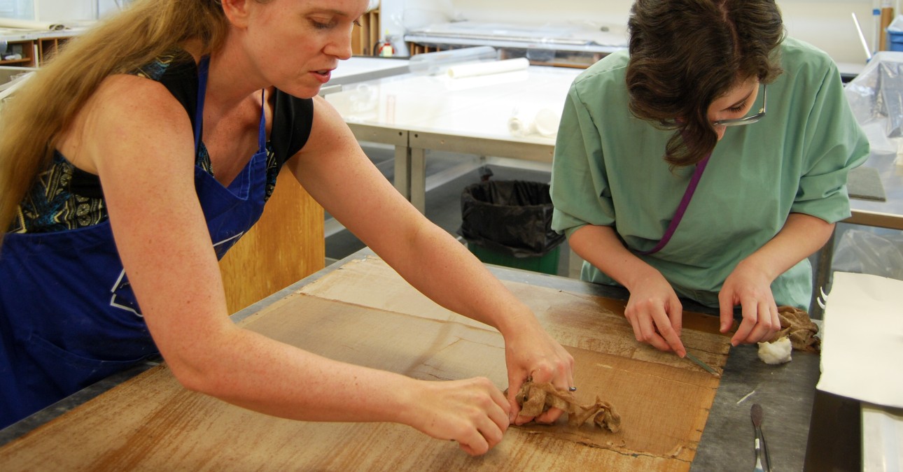 Conservators remove backing from a large print