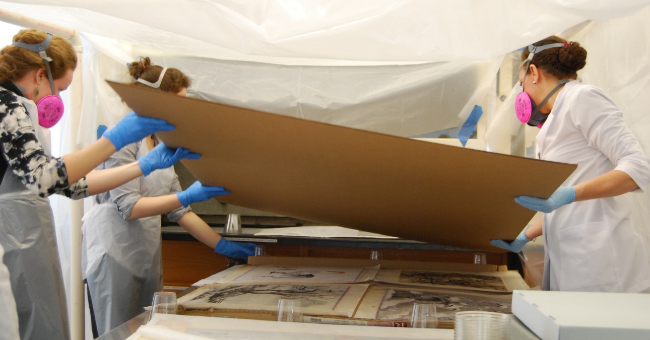 Conservators in masks and gloves dehumidify paintings