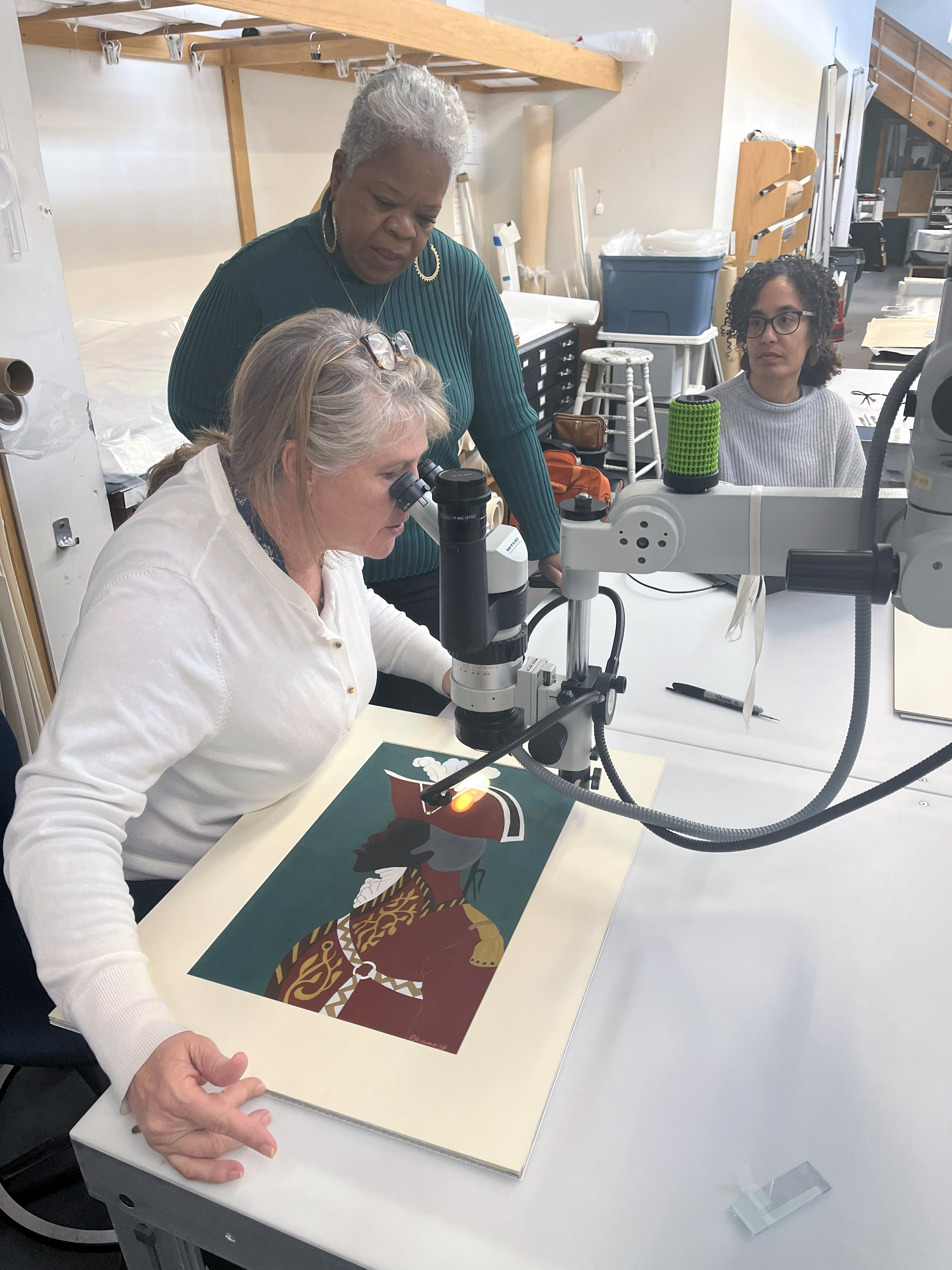From left: Joy Mazurek, Kathe Hambrick, and Ashley Freeman examine a painting by Jacob Lawrence