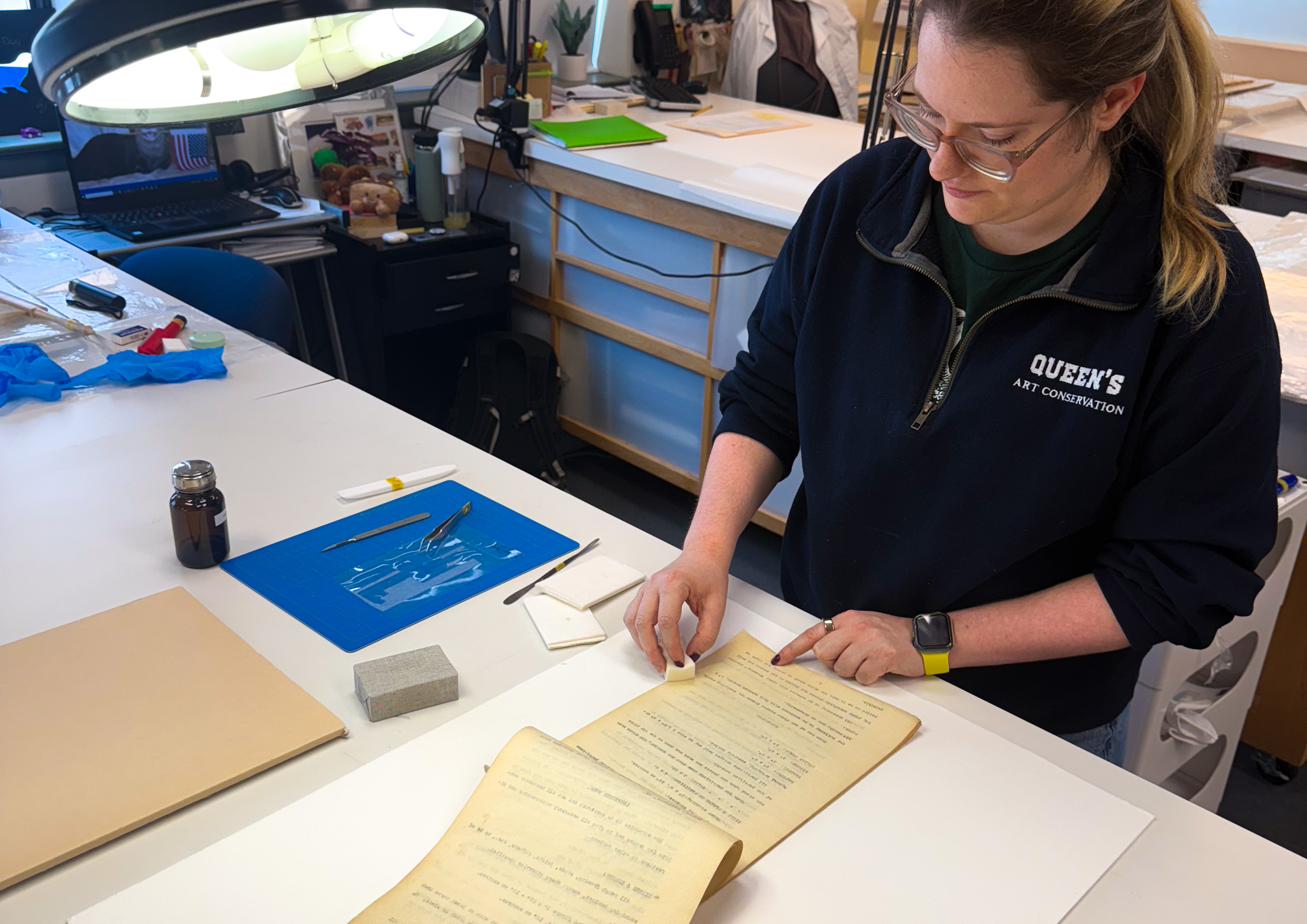Sandrine Blais, wearing a black sweater, treats a document with a sponge